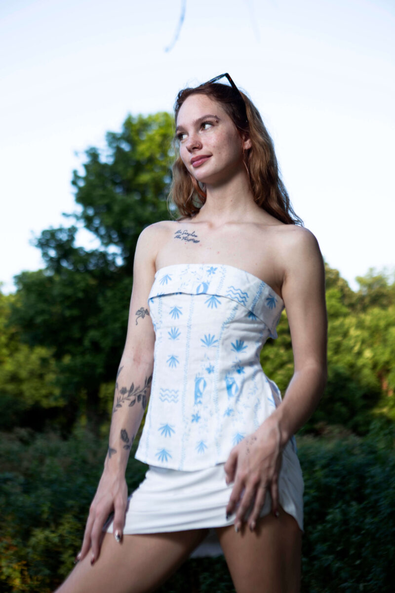 Outdoor portrait of a woman wearing a white patterned strapless top and white skirt surrounded by lush greenery at Ray Trent Park in Del City, photographed with soft natural light.