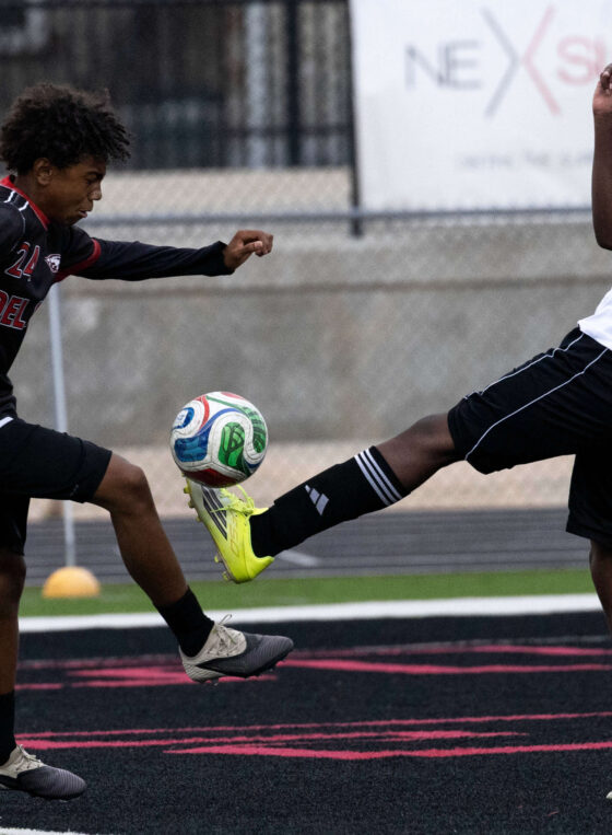 Midwest City and Del City high school soccer players contesting the ball mid-air during an intense match
