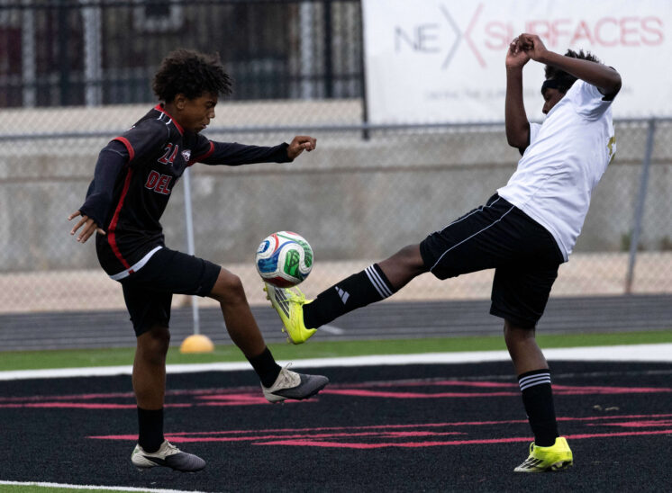 Midwest City and Del City high school soccer players contesting the ball mid-air during an intense match