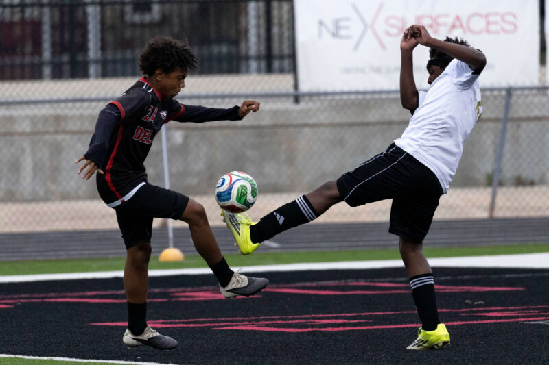 Midwest City and Del City high school soccer players contesting the ball mid-air during an intense match