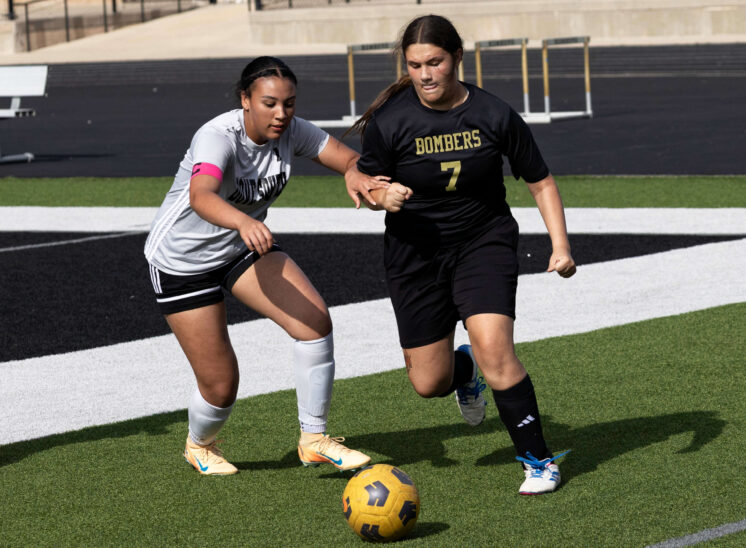 Midwest City middle school girls soccer player in black uniform dribbling the ball while being challenged by a defender