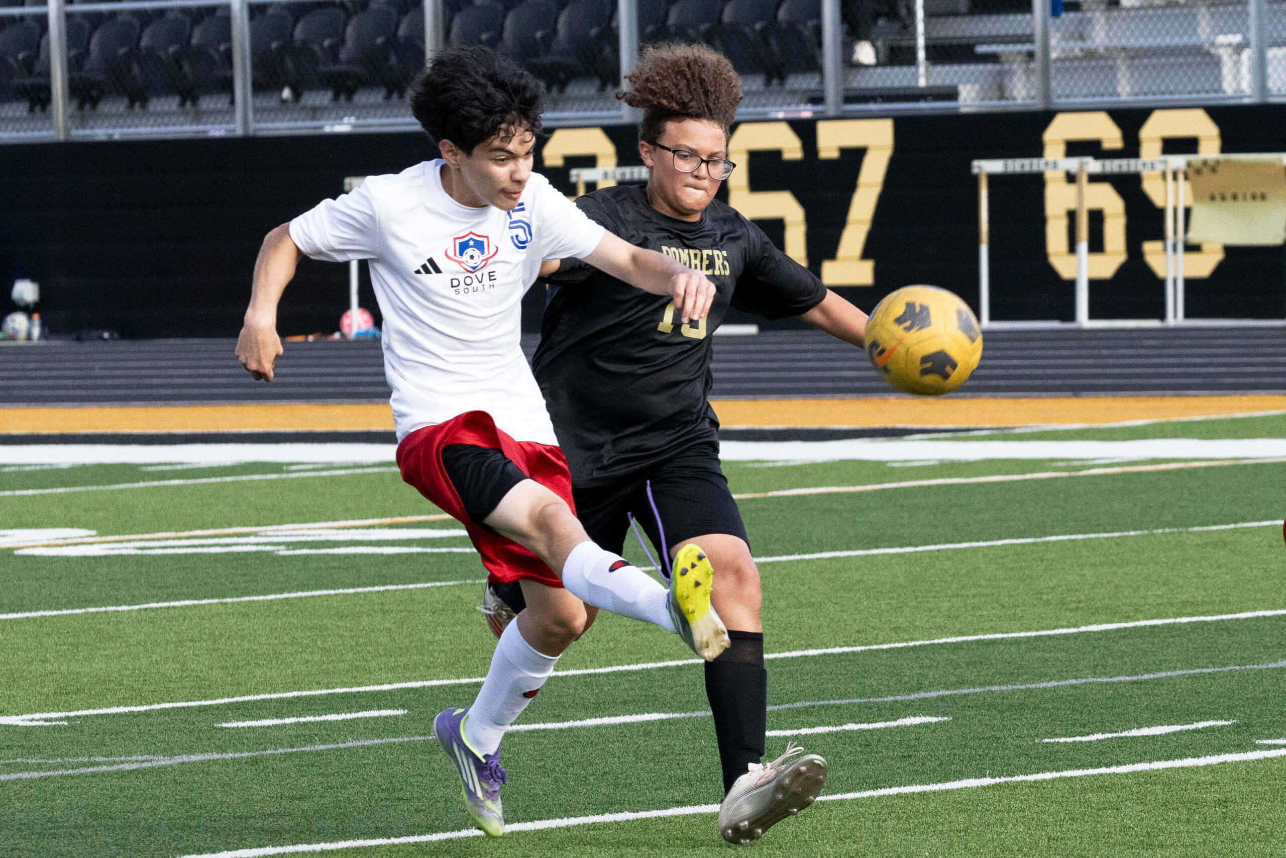Midwest City middle school boys soccer player in black challenges a Dove Academy player for the ball during a match