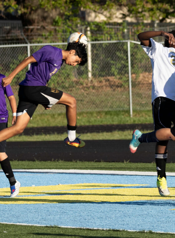 youth soccer player heading ball while defender challenges Oklahoma sports photography