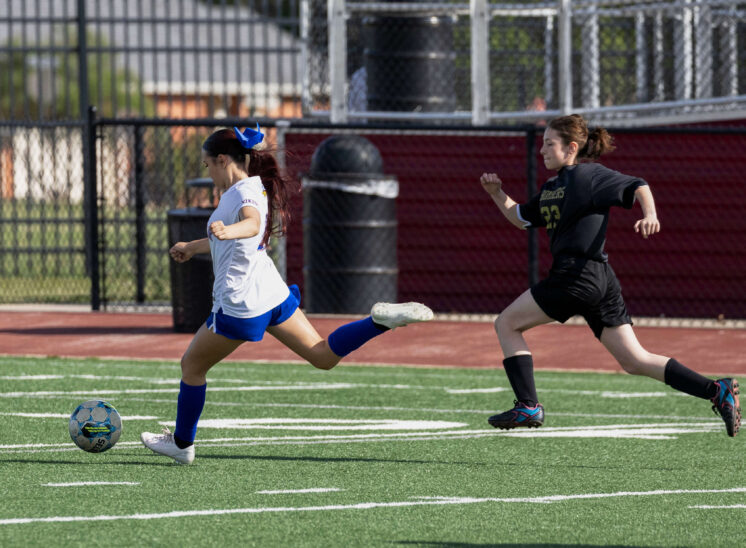 Midwest City Bombers girls soccer player sprinting with the ball while a Bomber defender chases during a match