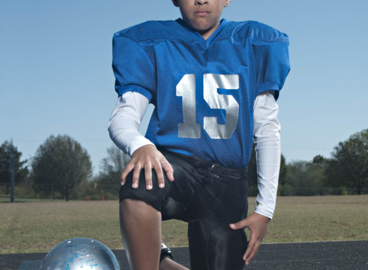 youth football player kneeling with helmet serious expression Guthrie Oklahoma sports portrait photography