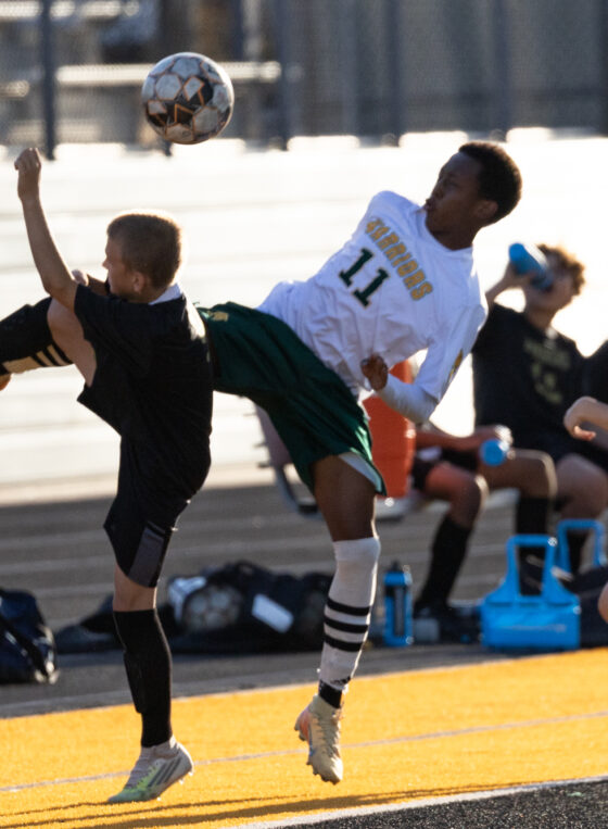 Midwest City middle school boys soccer players in black challenge a Western Oaks player in white for an airborne ball