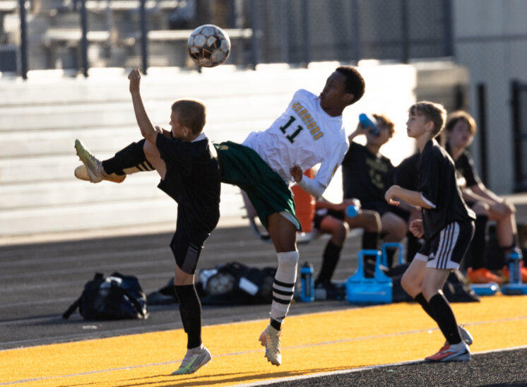 Midwest City middle school boys soccer players in black challenge a Western Oaks player in white for an airborne ball