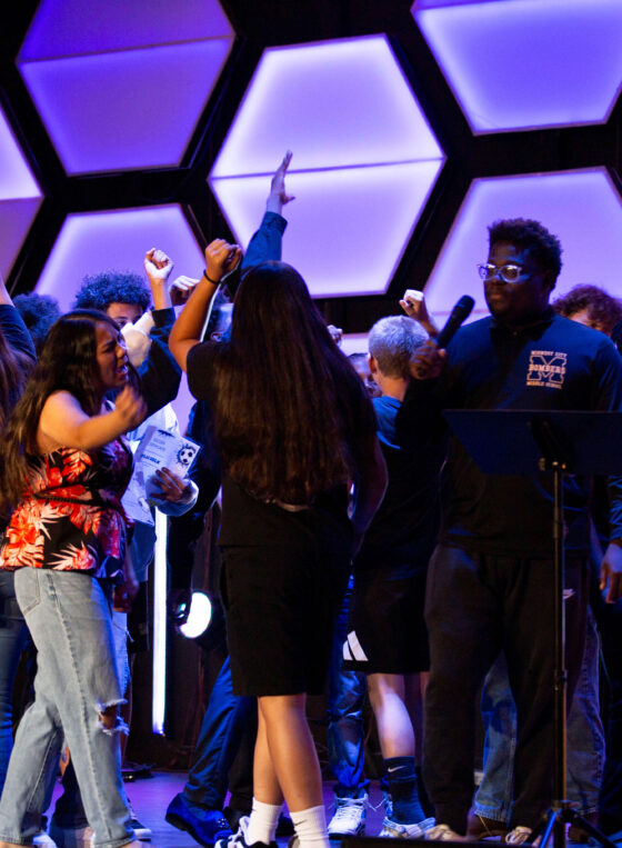 Midwest City Middle School boys and girls soccer players gather on stage with raised hands while reciting their team chant during the 2026 team banquet at People's Church.