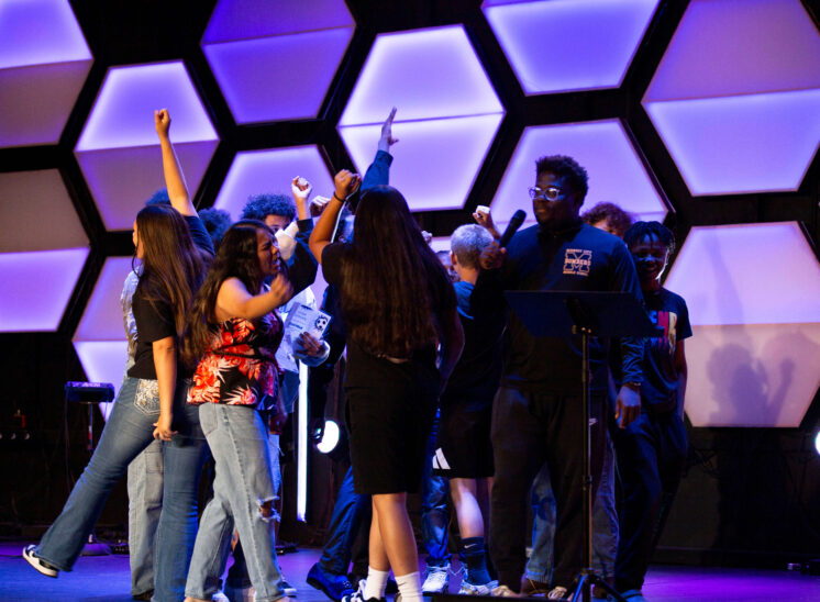 Midwest City Middle School boys and girls soccer players gather on stage with raised hands while reciting their team chant during the 2026 team banquet at People's Church.