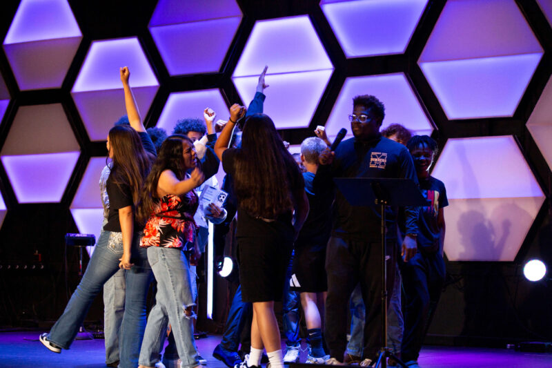 Midwest City Middle School boys and girls soccer players gather on stage with raised hands while reciting their team chant during the 2026 team banquet at People's Church.