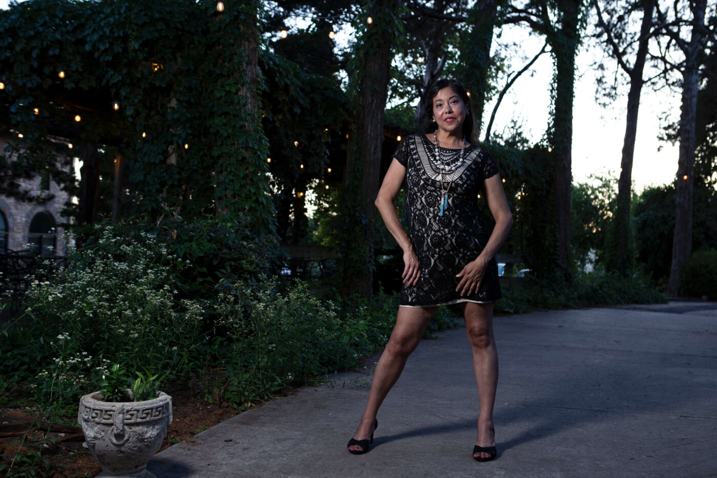 Full-body portrait of a woman in a black lace dress standing along a garden pathway at Castle Falls during a 1940s-themed photography event.