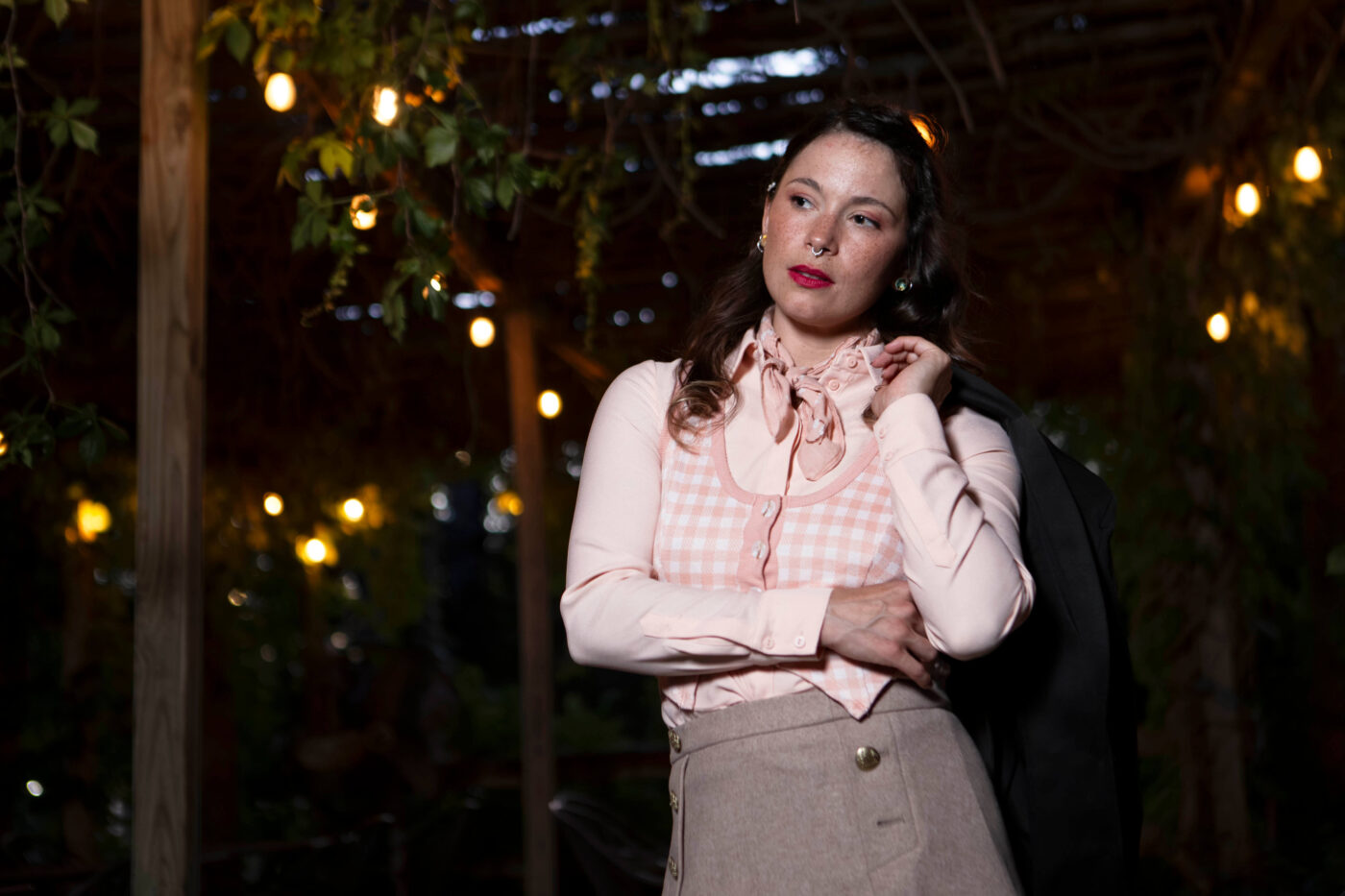 Close portrait of Gema Khaos beneath glowing string lights at Castle Falls wearing a pastel vintage-inspired outfit during a 1940s photomeet.