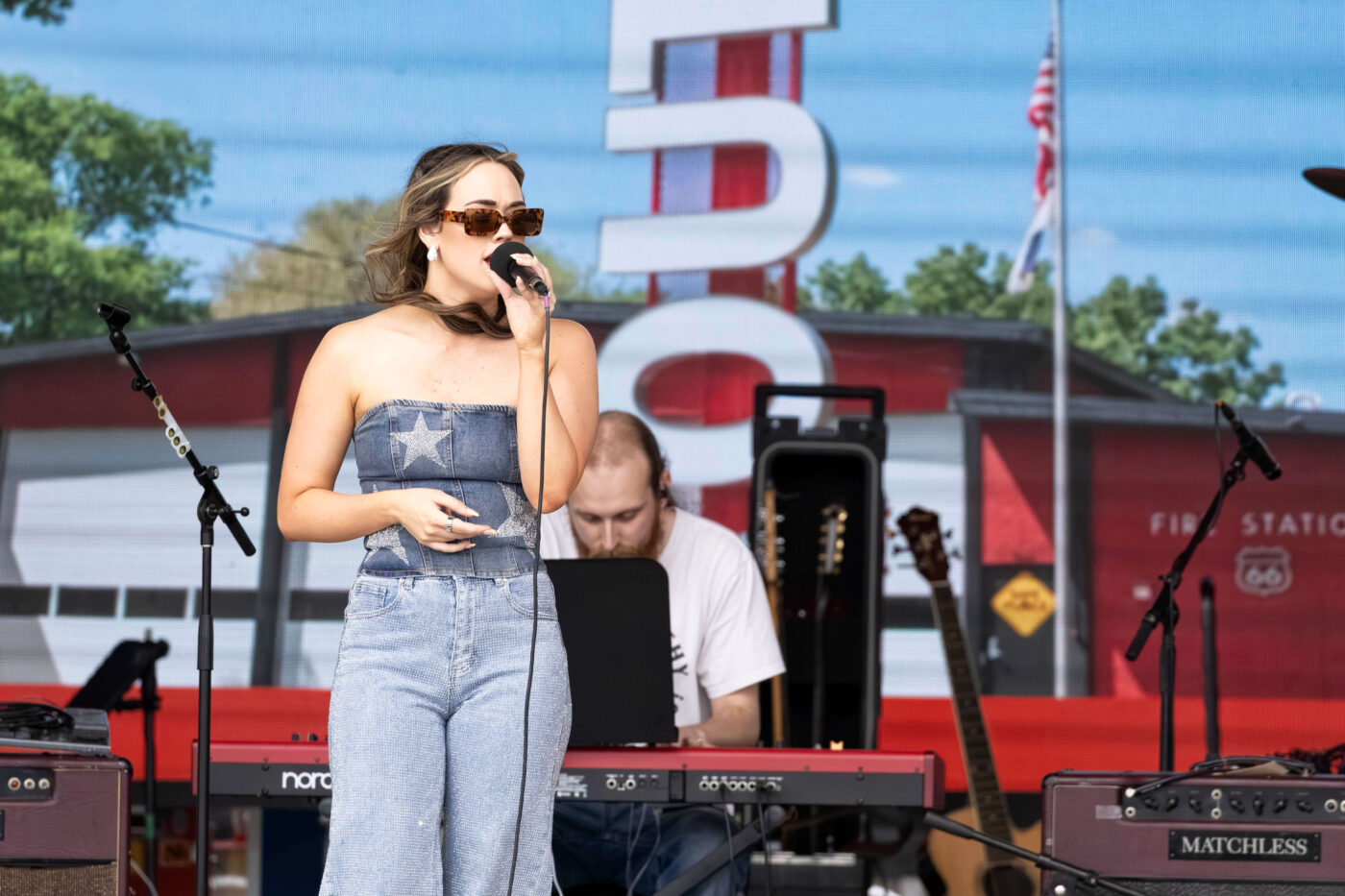 OK3 vocalist sings in front of a Route 66-themed stage backdrop during the Oklahoma City celebration.