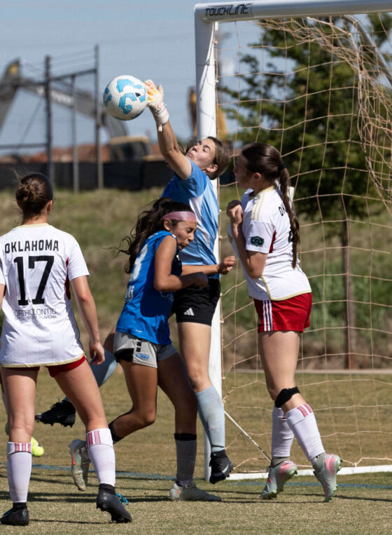 Amarillo Rush attacker in blue challenges for the ball near the goal as the Oklahoma Energy goalkeeper reaches for a save during the U16 Girls Gold Division Final at the 2026 NOKC Spring Finale