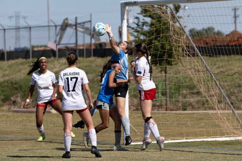 Amarillo Rush attacker in blue challenges for the ball near the goal as the Oklahoma Energy goalkeeper reaches for a save during the U16 Girls Gold Division Final at the 2026 NOKC Spring Finale