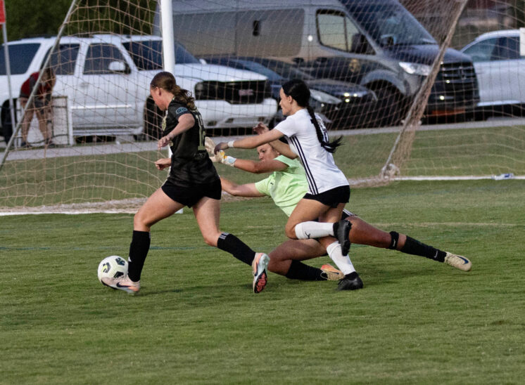 Midwest City Vision player in black attacks near the goal while an Oklahoma Energy defender and goalkeeper attempt to stop the play during a U16 Girls Gold Division match at the 2026 NOKC Spring Finale