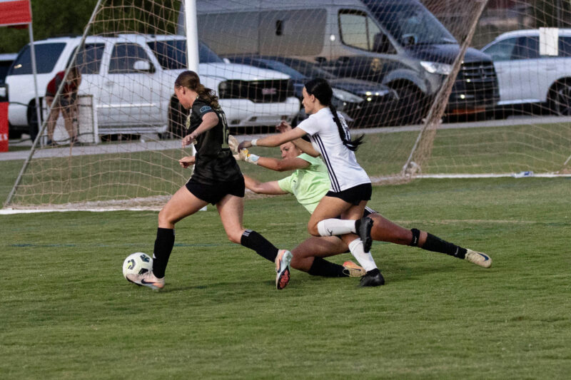 Midwest City Vision player in black attacks near the goal while an Oklahoma Energy defender and goalkeeper attempt to stop the play during a U16 Girls Gold Division match at the 2026 NOKC Spring Finale