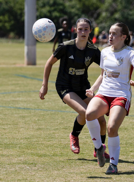 West Side Alliance SC player in white tracks the ball while a Midwest City Vision defender in black closes in during a U16 Girls Gold Division match at the 2026 NOKC Spring Finale