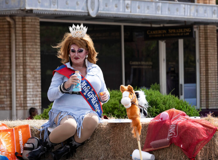 Performer wearing a crown and sash rides on a parade float during the Oklahoma City Pride Parade.