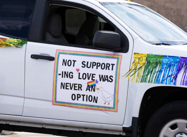 Decorated vehicle displays a sign promoting love and acceptance during the parade.