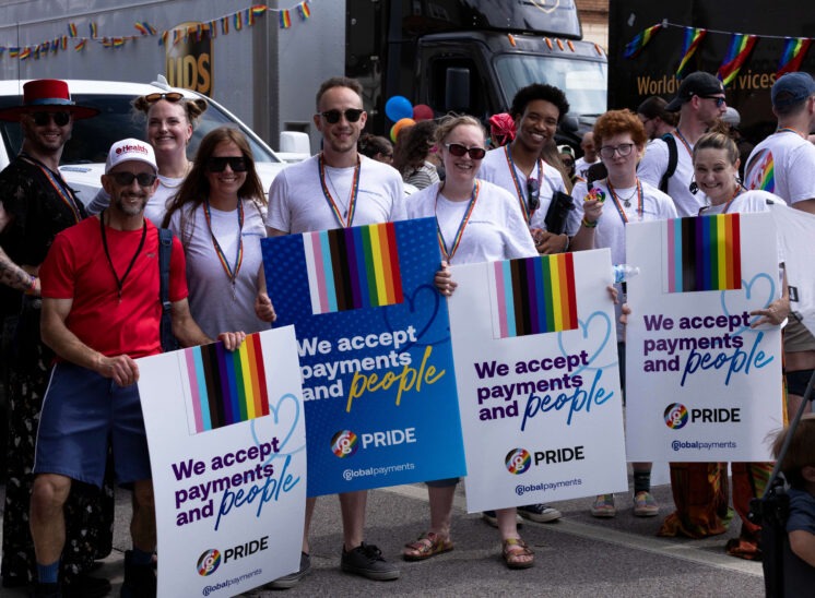 Group of parade participants hold signs promoting acceptance and inclusion.