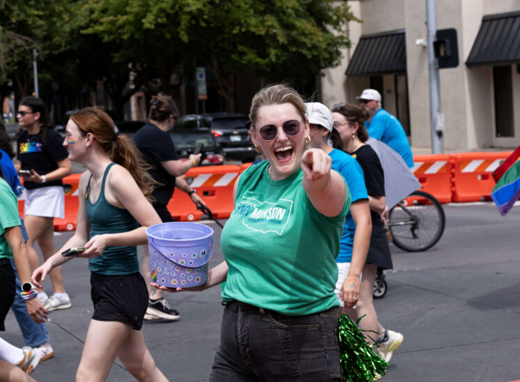 A parade participant points toward the camera while smiling during the Oklahoma City Pride parade.