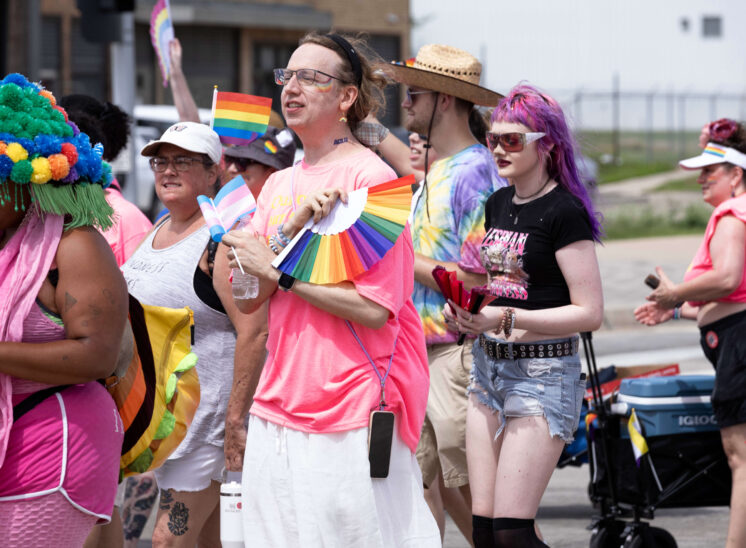 Parade participants carry rainbow-themed accessories and flags while walking through the Oklahoma City Pride parade.