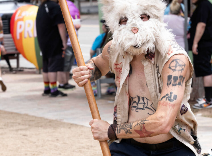 A costumed attendee wearing a rabbit mask carries a large prop mallet at the Pride festival.