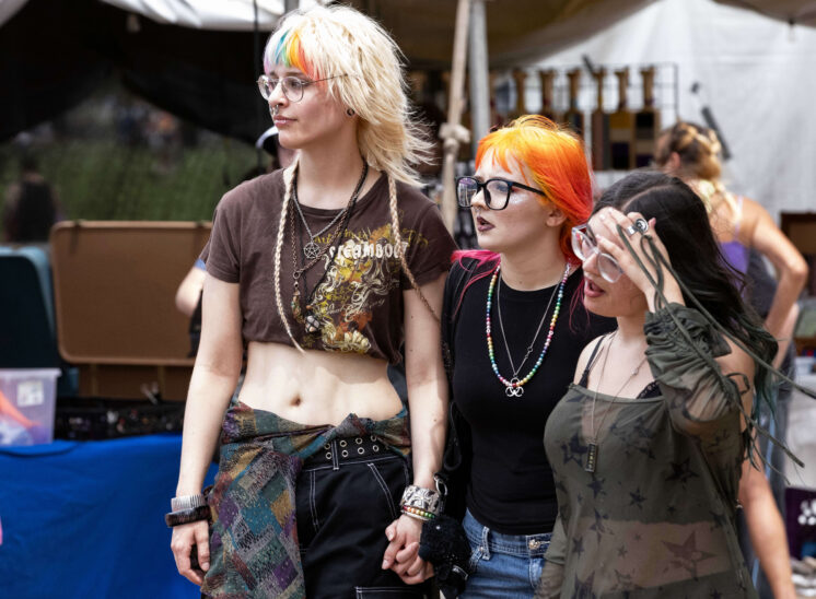 Three festival attendees walk together through vendor booths at Oklahoma City Pride.