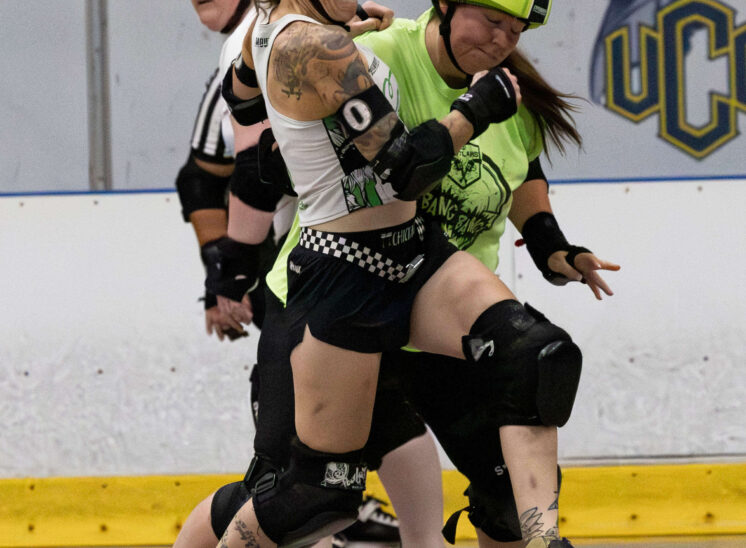 Capital City Crushers and Twister City Roller Derby Outlaws skaters battle for position during a physical roller derby jam.
