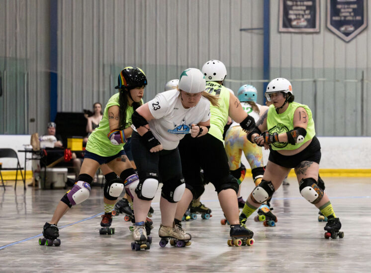 Capital City Crushers jammer battles through Outlaws defenders during an intense roller derby jam.