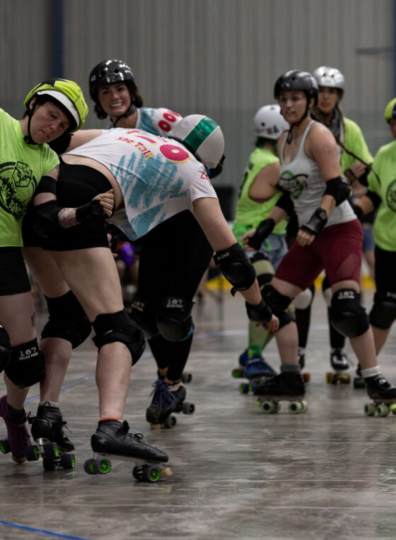 Outlaws blocker delivers contact to a Capital City Crushers skater during a roller derby jam.