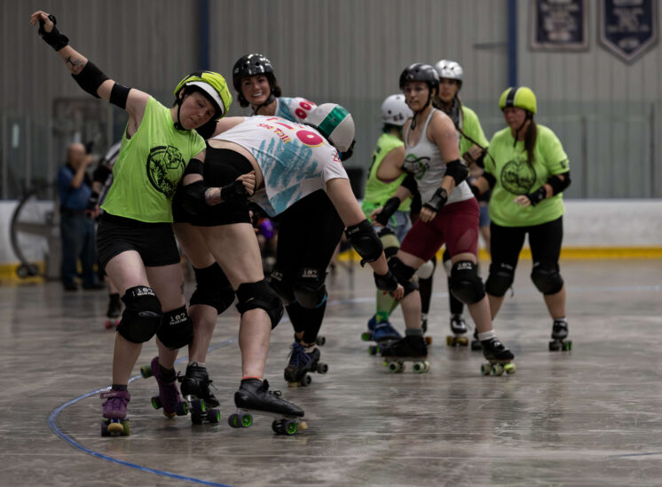 Outlaws blocker delivers contact to a Capital City Crushers skater during a roller derby jam.