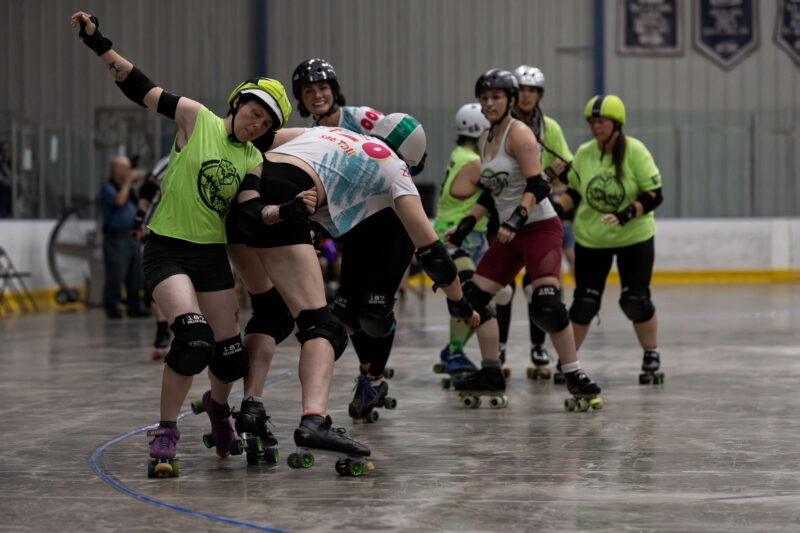 Outlaws blocker delivers contact to a Capital City Crushers skater during a roller derby jam.
