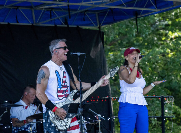 Lead vocalist and bassist performing during a live outdoor concert.