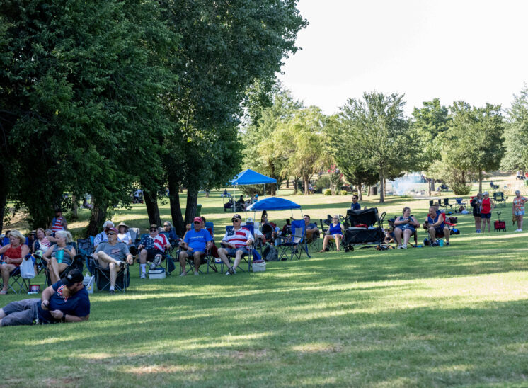 Families and visitors seated in lawn chairs watching live entertainment.