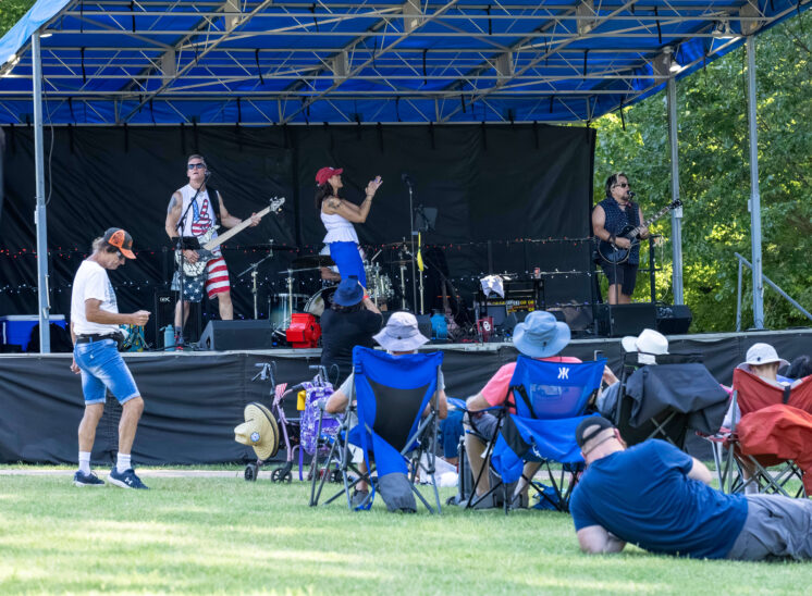 Audience members watching Super Freak perform from the lawn area.