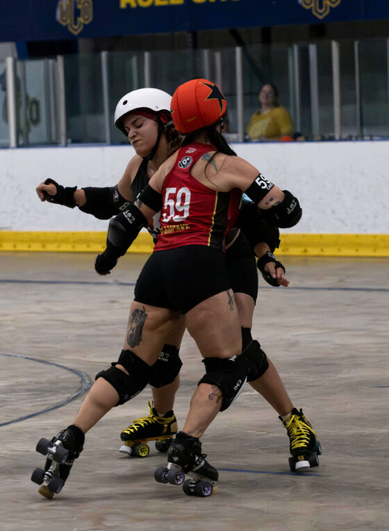Memphis A skater #59 engages a Twister City blocker during a one-on-one battle on the roller derby track.