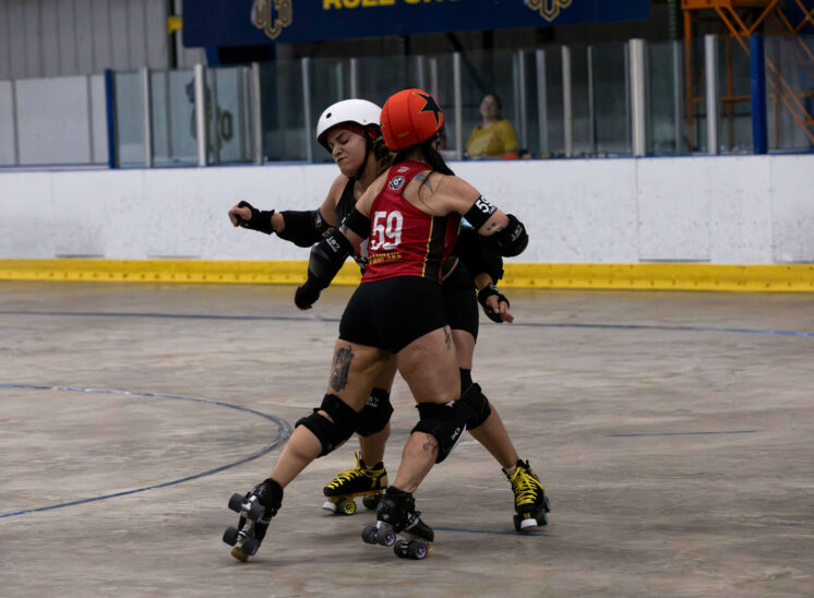 Memphis A skater #59 engages a Twister City blocker during a one-on-one battle on the roller derby track.