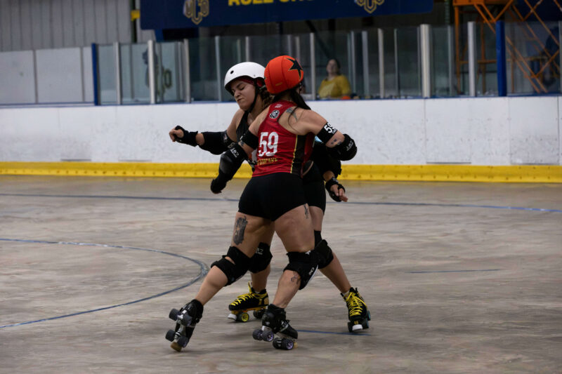 Memphis A skater #59 engages a Twister City blocker during a one-on-one battle on the roller derby track.