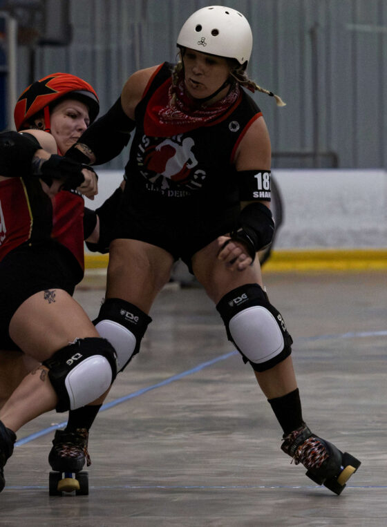 Twister City skater delivers a strong block against a Memphis A opponent during roller derby competition.