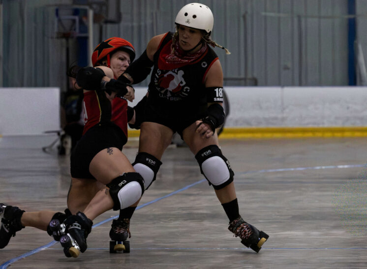 Twister City skater delivers a strong block against a Memphis A opponent during roller derby competition.