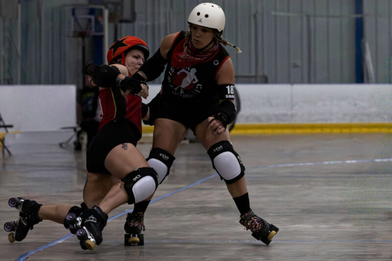 Twister City skater delivers a strong block against a Memphis A opponent during roller derby competition.